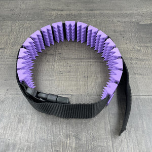 Een BDSM cilice met een zwarte band en lila spikes