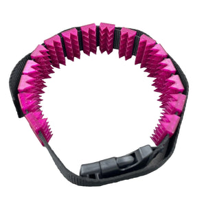 Een BDSM cilice met een zwarte band en spikes in de kleur magenta met glitters