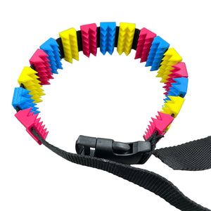 Een BDSM cilice met een zwarte band en spikes in de kleuren van de non-binaire vlag