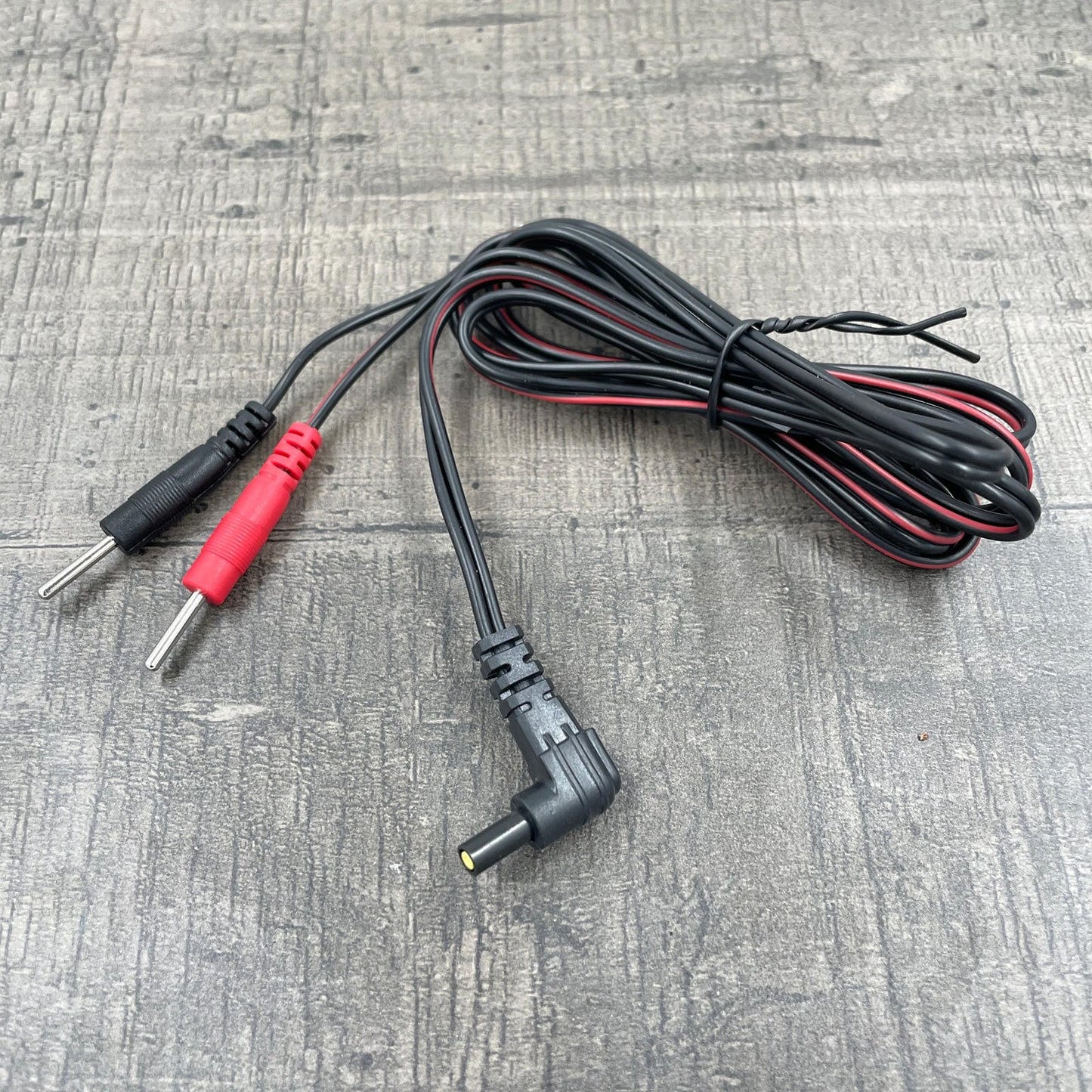 Een zwarte kabel voor e-stim producten met een Mystim plug en twee 2mm pluggen