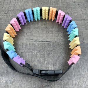 Een BDSM cilice met een zwarte band en spikes in pastelkleuren