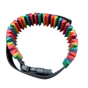Een BDSM cilice met een zwarte band en spikes in regenboogkleuren met glitters