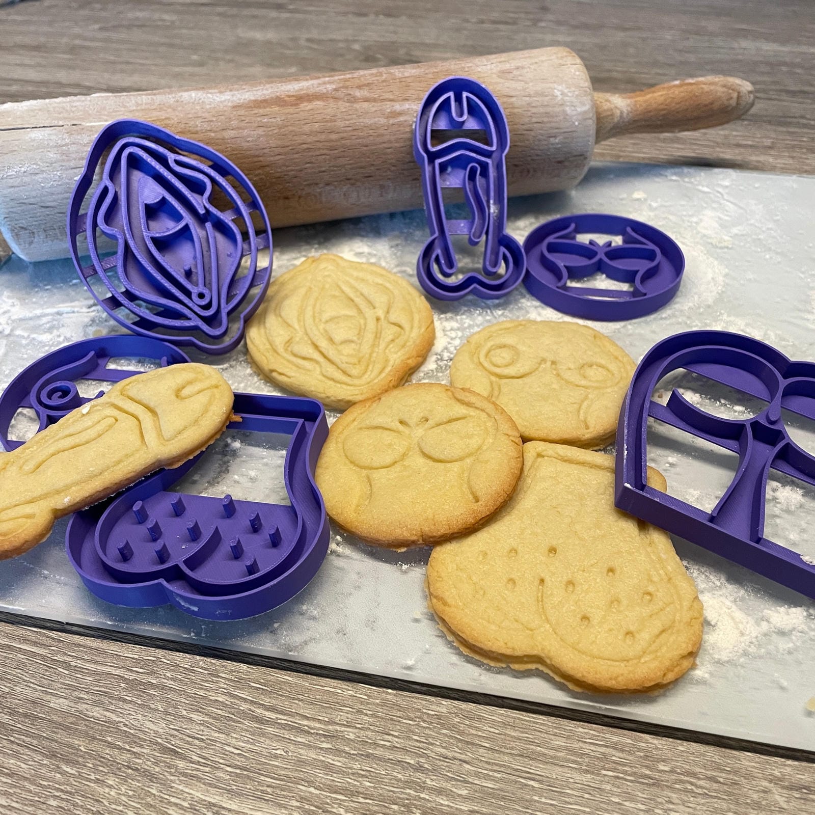 Koekjes en paarse bakvormpjes met de vormen van verschillende intieme lichaamsdelen