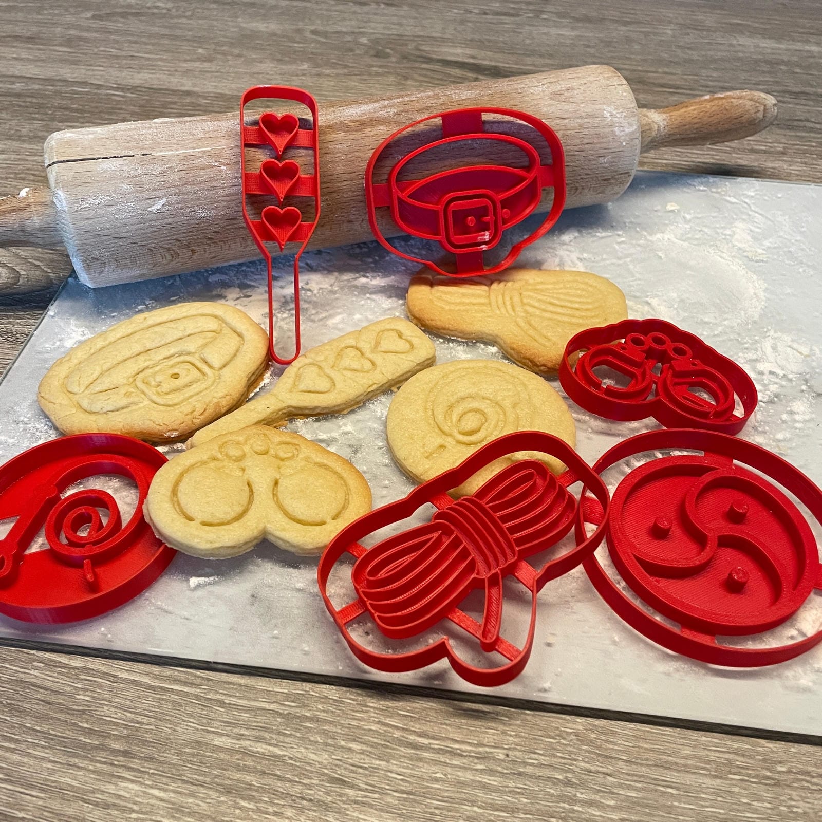 Koekjes en rode bakvormpjes met de vormen van verschillende BDSM speeltjes