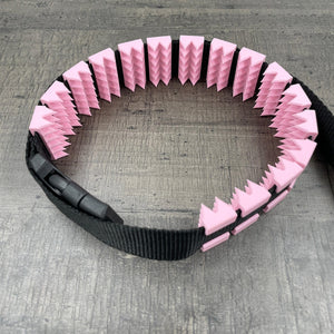 Een BDSM cilice met een zwarte band en spikes in de kleur roze
