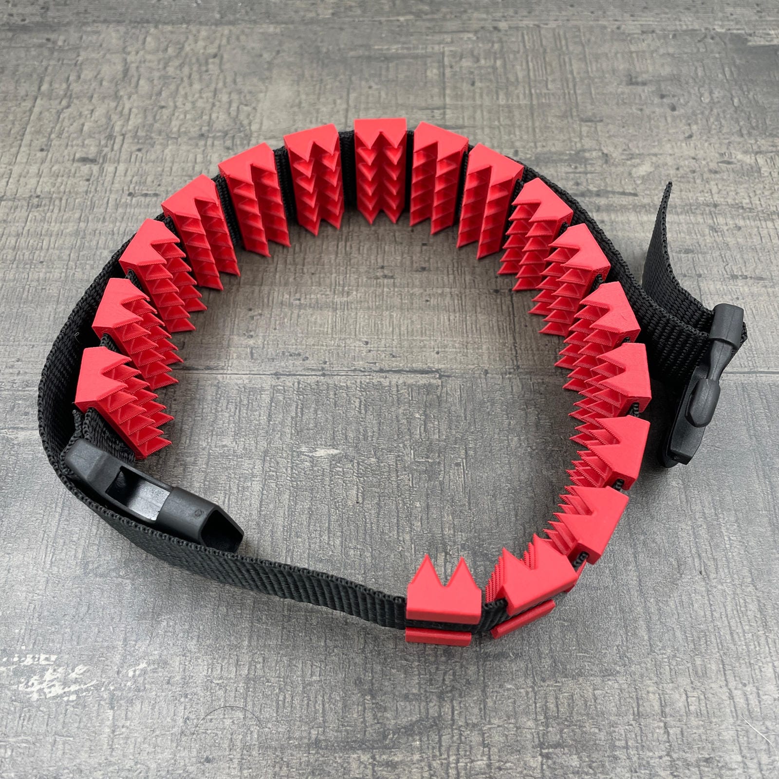 Een BDSM cilice met een zwarte band en spikes in de kleur rood