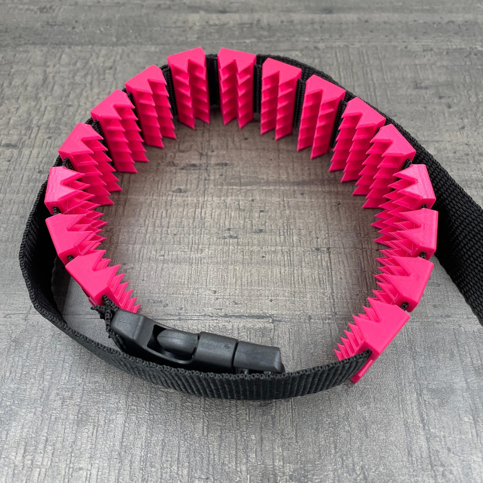 Een BDSM cilice met een zwarte band en spikes in de kleur magenta