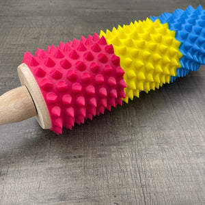 Een deegroller met spikes voor BDSM in de kleuren van de pan-seksuele vlag