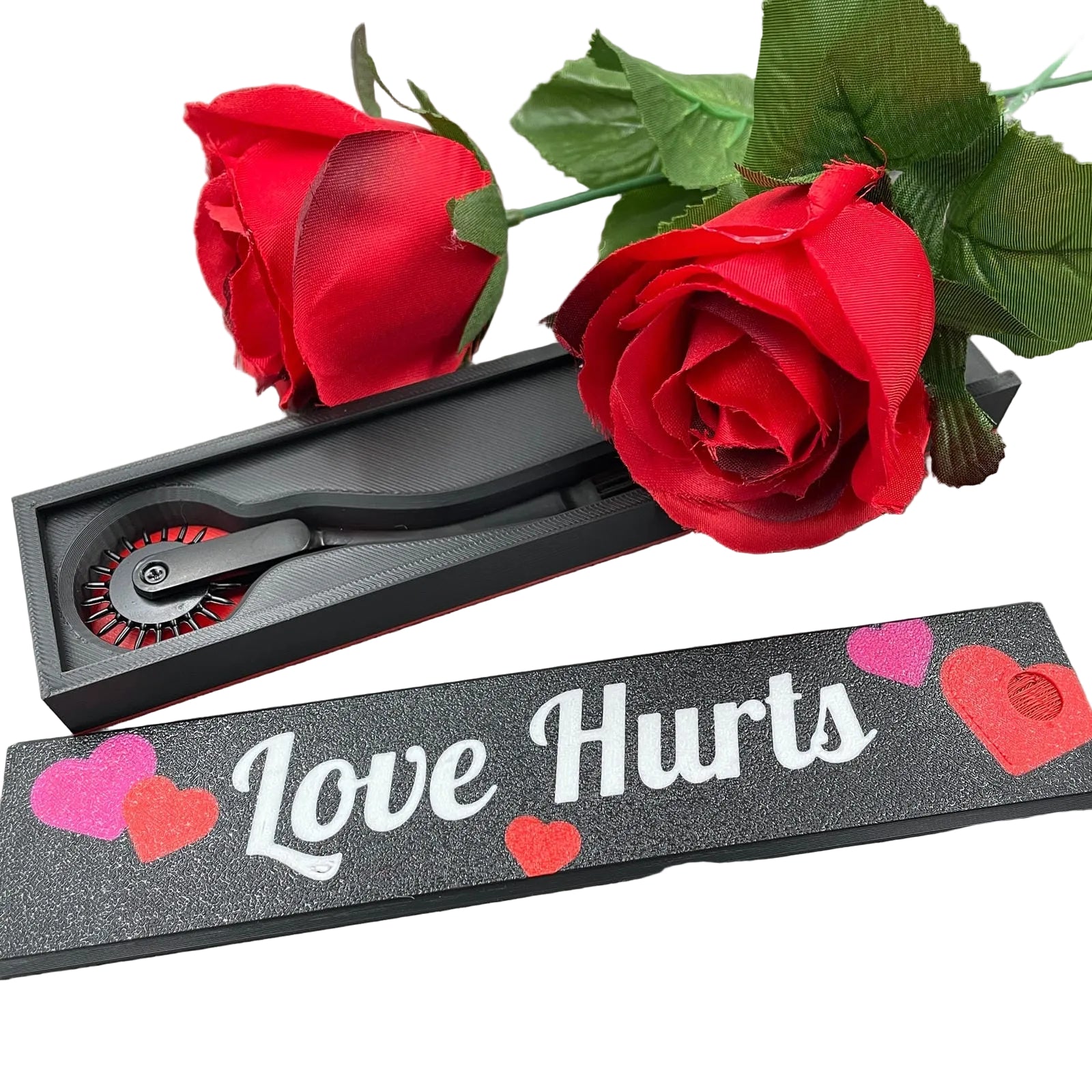 Een BDSM Wartenberg pinwheel in een doosje met de tekst "Love Hurts" en twee rozen
