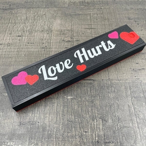 Een doosje met de tekst "Love Hurts"