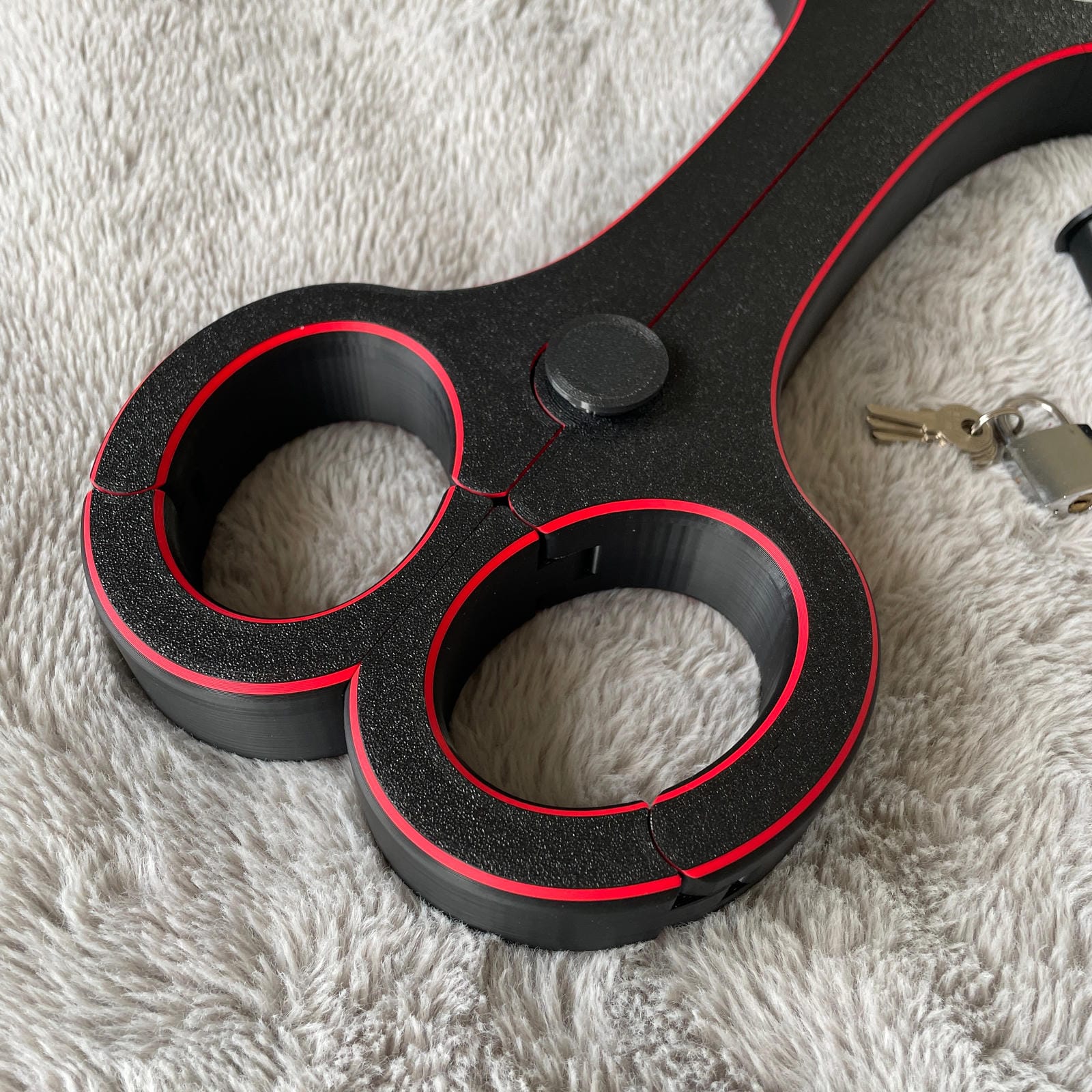 Detailfoto van de polsen van een BDSM rigid fiddle in het zwart met rode accenten