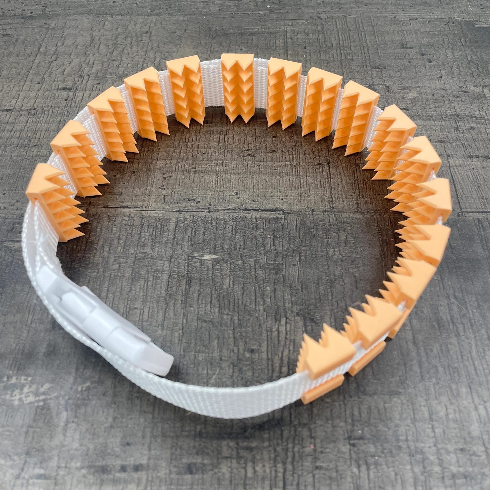 Een BDSM cilice met een witte band en oranje spikes