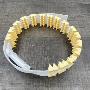 Een BDSM cilice met een witte band en gele spikes