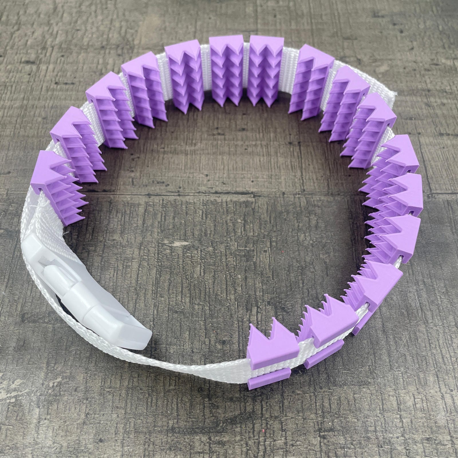 Een BDSM cilice met een witte band en paarse spikes