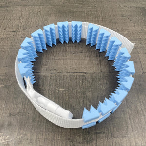 Een BDSM cilice met een witte band en lichtblauwe spikes