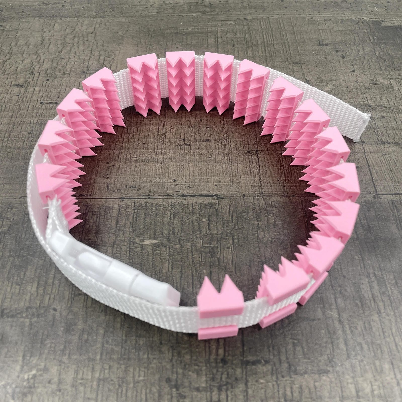 Een BDSM cilice met een witte band en roze spikes