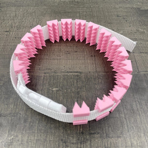 Een BDSM cilice met een witte band en roze spikes