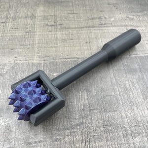 Een BDSM pinwheel met een zwart handvat en paars wieltje met glitters