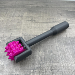 Een BDSM pinwheel met een zwart handvat en een wieltje in magenta met glitters