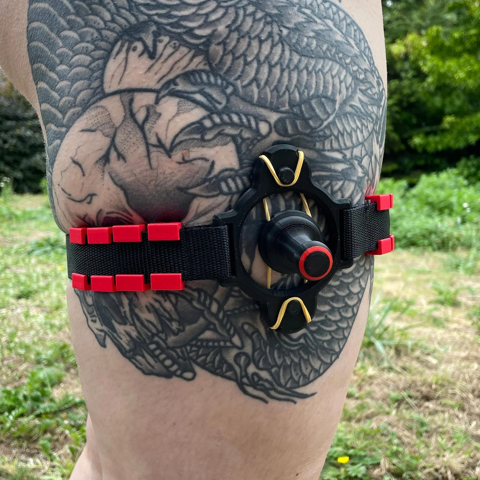 Een zwarte band met een BDSM impact speeltje met spikes om het been van een persoon