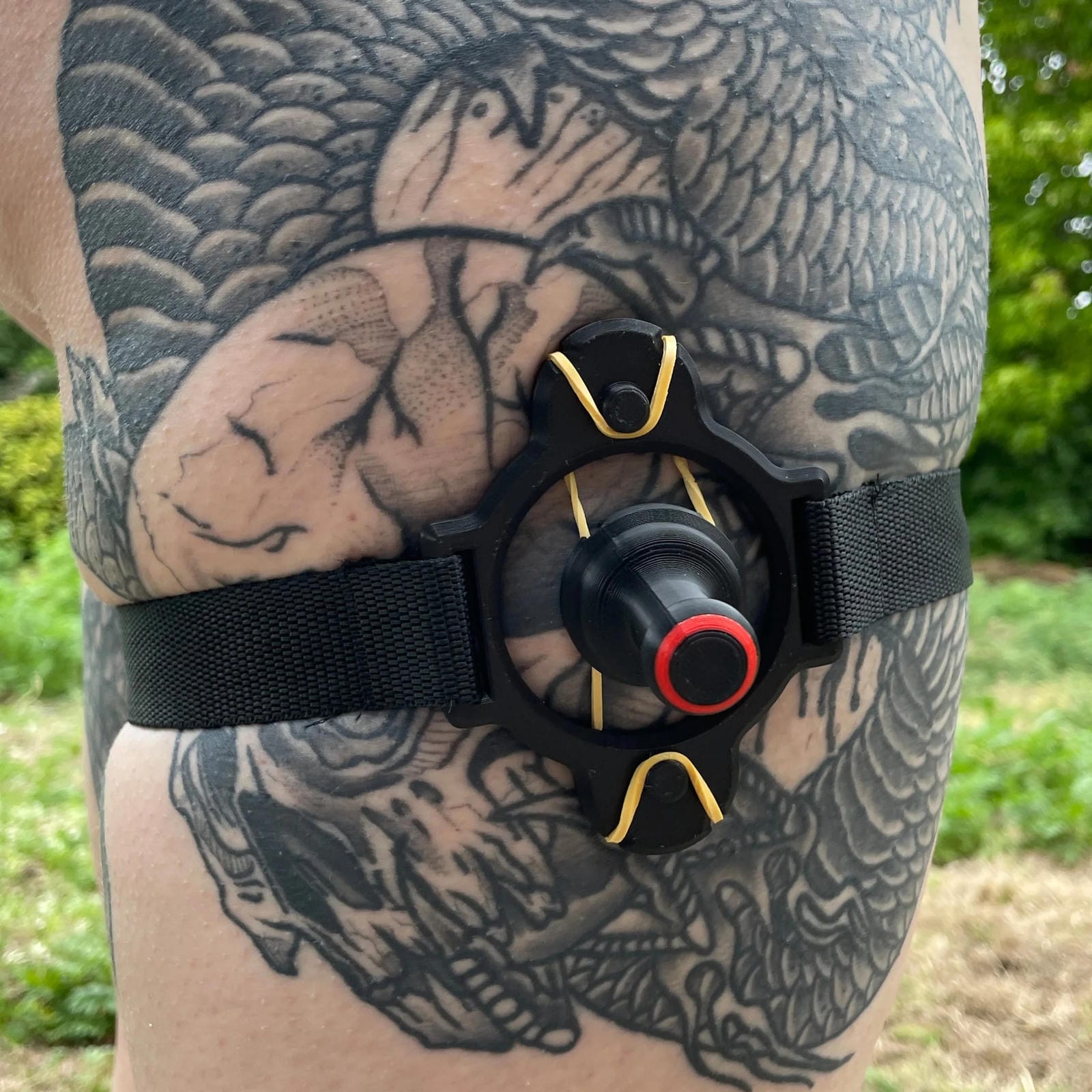 Een zwarte band met een BDSM impact speeltje met spikes om het been van een persoon